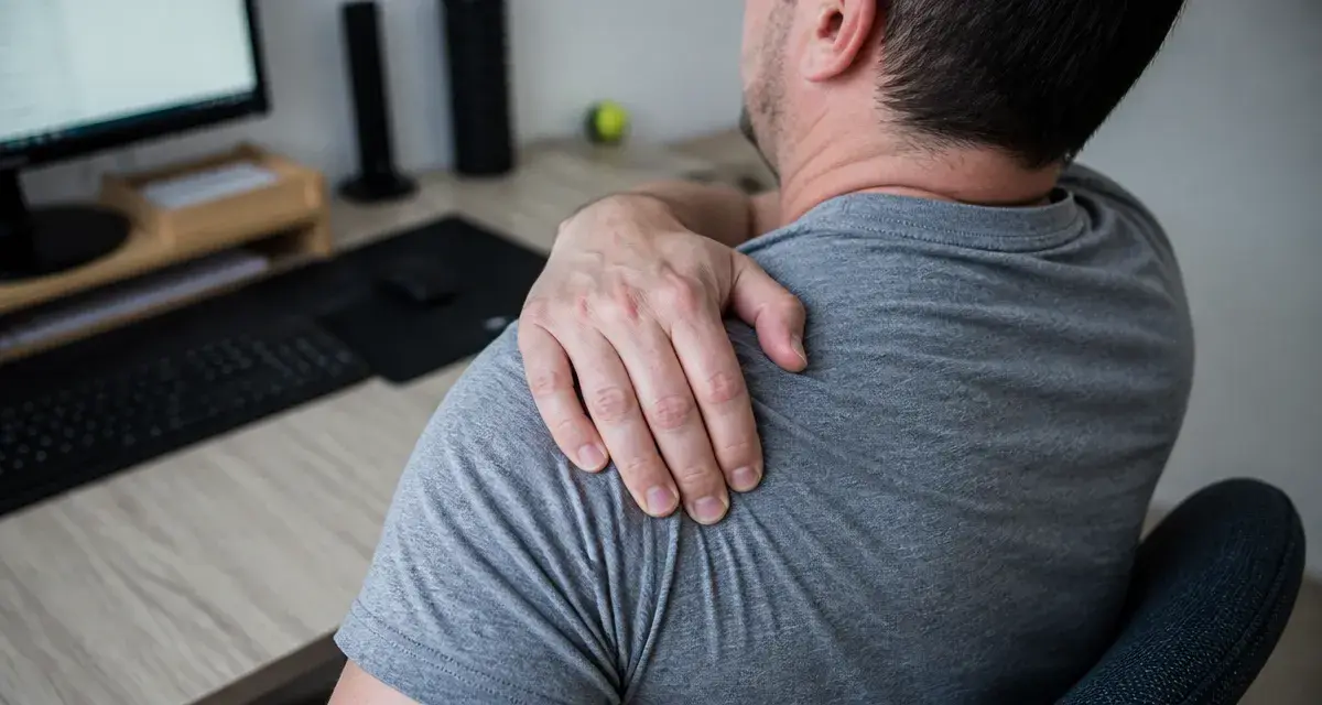 Douleur omoplate droite : main sur l’omoplate au bureau